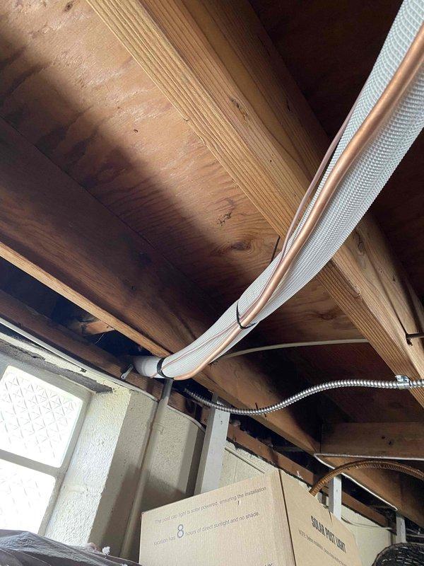 Completed full HVAC system installation including outdoor condensing unit with proper electrical disconnect, refrigerant line set, and fabric duct distribution system. Installed and wired disconnect box on exterior wall with flexible conduit connection to compressor unit, positioned unit on gravel pad for proper drainage and clearance, and evacuated and charged system with refrigerant to manufacturer specifications. Routed fabric ductwork through floor joists with metallic transitions to ensure proper airflow distribution throughout conditioned space.