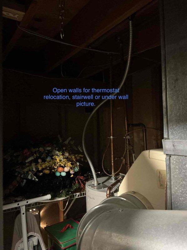 Performed site evaluation for thermostat relocation in residential property. Assessed existing Trane air handler installation, documented current wiring configuration and metal ductwork routing through basement utility area. Identified optimal pathways through open wall cavities near stairwell for new thermostat wire run, photographed accessible routing options and marked ductwork connections for future installation work.