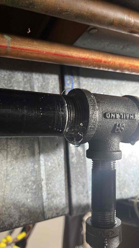 Completed gas line installation in preparation for propane tank and HVAC system connection scheduled for the following week. Installed black iron pipe fittings including T-junction connections with proper threading, routed gas piping through basement mechanical space alongside existing copper water lines and HVAC ductwork. All components installed to code specifications with appropriate support brackets and secured to structural elements for safe operation of future gas appliances.
