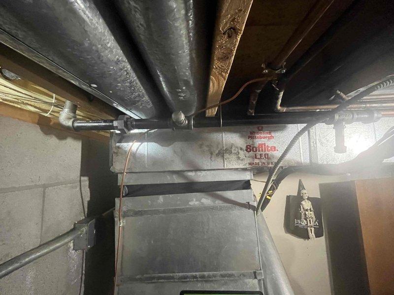 Completed gas line installation in preparation for propane tank and HVAC system connection scheduled for the following week. Installed black iron pipe fittings including T-junction connections with proper threading, routed gas piping through basement mechanical space alongside existing copper water lines and HVAC ductwork. All components installed to code specifications with appropriate support brackets and secured to structural elements for safe operation of future gas appliances.
