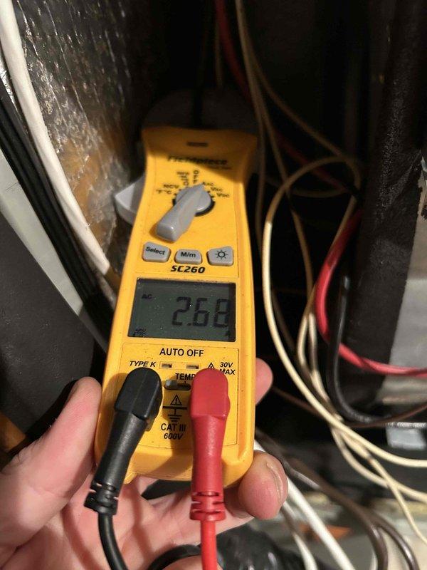 Responded to emergency no-heat call for four-year-old heat pump system. Upon arrival, performed diagnostic testing of the HVAC unit located in basement mechanical room. Utilized digital multimeter to measure electrical readings and verify proper voltage supply to system components. Reading of 2.68 displayed on meter during troubleshooting process indicated potential issue with electrical circuit or component performance. Inspected furnace/air handler unit, noting normal wear and dust accumulation consistent with four years of operation. Examined ductwork connections, thermostat operation, and associated plumbing lines. Documented equipment condition through photography for service records. System evaluated for proper operation of heat pump components and auxiliary heating elements.