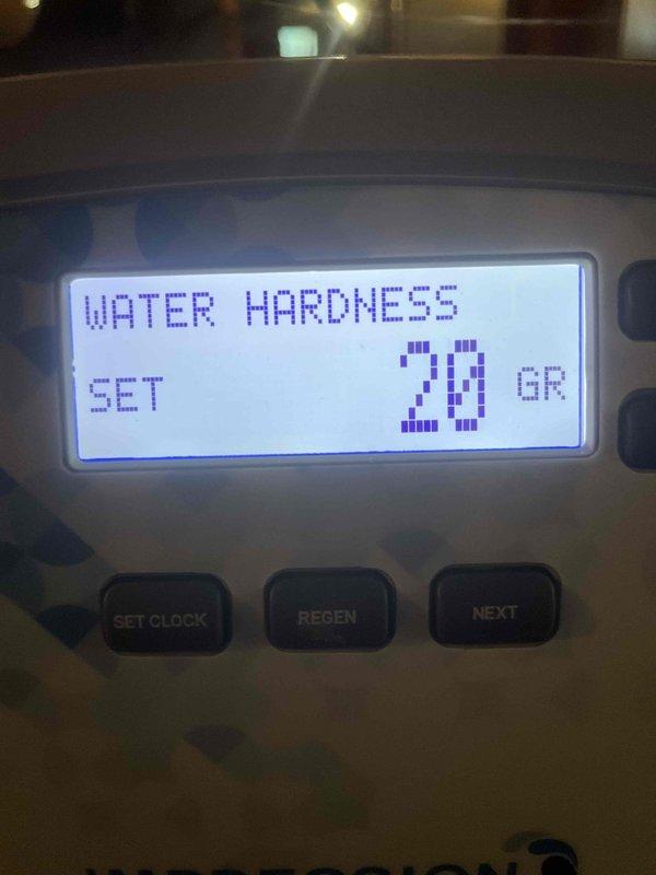 Responded to callback for water treatment system previously installed by our company. Upon arrival, inspected water softener control head and found hardness setting programmed at 20 grains. Verified system programming and operational parameters. Checked downstream plumbing fixtures for evidence of continued hard water issues. Examined toilet tank interior and documented significant mineral deposits and rust staining on porcelain surfaces, indicating ongoing water quality concerns. System appears to be functioning mechanically but may require adjustment to regeneration cycle or hardness settings to adequately treat incoming water supply. Photographed control panel display and affected fixtures for documentation.