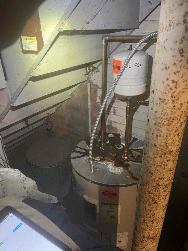Responded to service call for multiple plumbing issues including unstable toilet fixture, aging water heater system, and malfunctioning shower diverter valve. Inspected toilet installation and found loose floor mounting bolts causing fixture movement. Evaluated water heater condition, noting significant corrosion on top connections and aging infrastructure requiring future replacement consideration. Assessed shower diverter valve malfunction allowing hot water bypass during shower operation. Documented equipment conditions with photographic evidence showing water heater with rust deterioration at pipe connections, corroded support column, and overall mechanical room infrastructure. Provided recommendations for toilet remounting, water heater replacement planning, and shower valve repair to address all identified deficiencies.