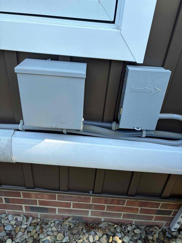 Completed boiler maintenance member visit and inspected HVAC system components. Documented air filter with significant frost and ice accumulation indicating potential airflow restriction or abnormal temperature conditions that may affect system performance. Photographed exterior electrical boxes and conduit installation, including DiversiTech component and PVC piping on building exterior for service records.