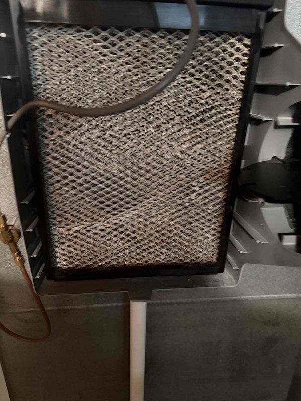 Replaced air filter in air purification system due to excessive dust accumulation and discoloration affecting filtration efficiency. Verified Aprilaire humidifier control unit operation and proper outdoor humidity sensor functionality with digital display readings within normal parameters.