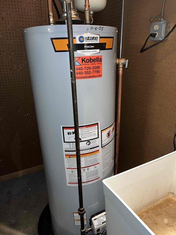 Completed plumbing membership visit and inspection of residential water heating system. Documented State ProLine commercial-grade tank-type water heater installation in utility room, confirming proper expansion tank connection and copper supply line configuration. Verified system operational status and captured equipment specifications for maintenance records.