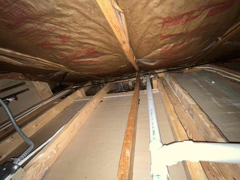 Returned to the site to evaluate the reported noise from the Navien boiler. Inspected the accessible framing cavities and surrounding piping, including the 1-1/2" DWV PVC drain/vent runs, fittings, and nearby wiring, and checked the surrounding insulation for loose or contacting components that could transmit sound. Documented the condition of the piping and support areas with photos to assist in diagnosing the source of the noise.