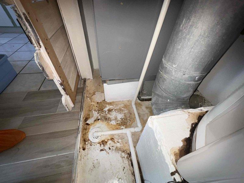Performed an on-site evaluation for HVAC system replacement of a closet-installed furnace/air handler with galvanized flue and ductwork, adjacent to a gas-fired water heater. Documented significant staining, mineral deposits, and moisture damage around the PVC condensate drain line and surrounding floor and door trim, indicating prior leakage or a condensate drainage deficiency. Replacement scope should include correcting condensate drainage and verifying flue, ductwork, and gas line connections.