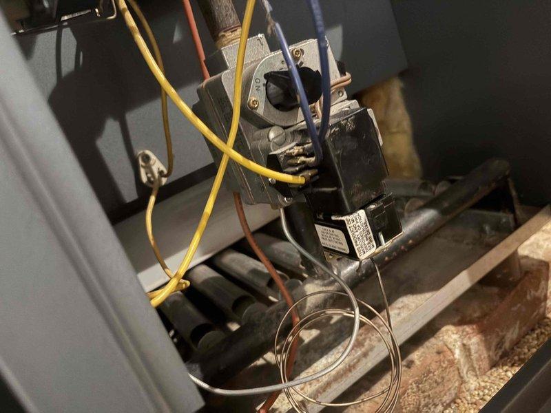 Responded to a no-heat call on a 1987 gas-fired boiler with a recurring mercury switch sticking issue and inspected the control compartment, gas control valve, and burner assembly. Found dirty, discolored terminal connections on the gas valve and soot accumulation on the burner tubes, with crumbling refractory material at the appliance base. System was evaluated for continued operation given its age, as the owner is attempting to keep it running another year.