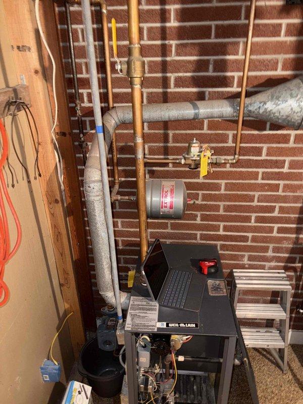 Performed a replacement estimate on a 1987 Weil-McLain boiler with a recurring mercury switch sticking issue, as the homeowner is evaluating whether to keep the unit operating another year. Inspected the open burner compartment, gas controls, wiring, Extrol expansion tank, copper supply/return piping, pressure relief valve, and galvanized flue, and documented typical age-related wear, surface darkening, and dust accumulation with no obvious breakage or leaks. Reviewed repair-versus-replacement options based on the system's age and condition.