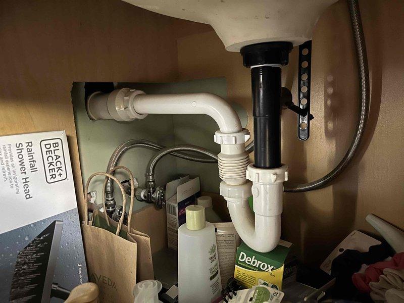 Inspected the reported non-functioning garbage disposal and evaluated the associated drain system for venting issues. Examination of the under-sink drain assembly, including the tailpiece, P-trap, slip-nut connections, and flexible trap arm to the wall, showed no leaks, corrosion, or visible damage. No bathroom sink components or photographed areas showed evidence of a disposal unit or a vent-related deficiency, so further diagnosis of the disposal and its venting is recommended at the kitchen fixture.