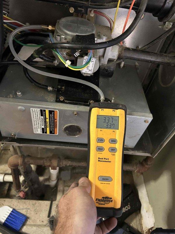 Responded to a no-heat complaint on the upstairs air handler unit blowing lukewarm air. Performed a combustion analysis (10.1% CO2, 92.4% efficiency) and verified gas manifold pressure with a digital manometer (3.37 in. w.c.) at the gas valve, confirming the furnace was firing within manufacturer specifications. Noted dusty, corroded gas piping and furnace interior conditions; system is operating and producing heat.