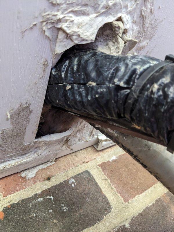 Inspected the line set and condensate/flex duct wall penetrations and found a split in the flexible duct jacket, deteriorated sealant around the soffit penetration, and damaged, flaking wall material at the exterior opening. Resealed the penetrations, secured the insulated line set bundle with zip ties, and restored the insulation and sealed gaps to prevent moisture and air infiltration and protect system efficiency.