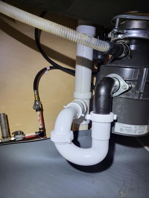 We responded to our customer due to them noticing a leak under the kitchen sink. Upon inspection, we found issues with the existing drain configuration connected to the garbage disposal. We cut and reworked the two inch PVC drain piping to allow for a proper and code compliant connection. A new p-trap was installed along with an air admittance valve to ensure proper drainage and venting. We also installed a new disposal outlet so the drain could run straight down into the trap, reducing the risk of future leaks or backups. All drain connections were aligned and securely fastened for proper flow. Once the repairs were complete, we ran the water and tested the entire assembly to confirm proper drainage and leak free operation.  