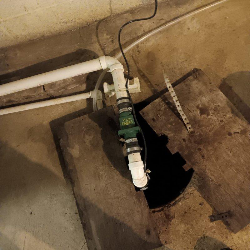 Completed estimate for replacement of existing wax ring and installation of a pump system to redirect laundry drain discharge to septic tank. Documented existing plumbing configuration in utility area, including washing machine location and current drainage setup. Installation will involve PVC piping connections to new green pump unit mounted on concrete floor with appropriate brackets and electrical connections.