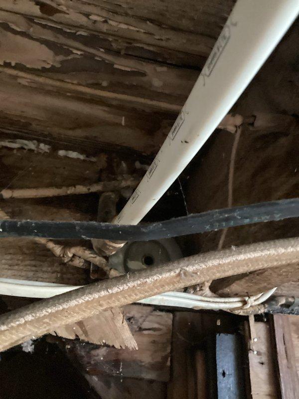 Responded to emergency water leak report in bathroom. Upon inspection, discovered significant water damage to wooden joists and structural elements in the crawlspace below, with visible deterioration and possible mold formation. Located source of leak at corroded copper pipe connection near glass block wall, replaced damaged section with new PVC fittings to restore proper function and prevent further structural damage.