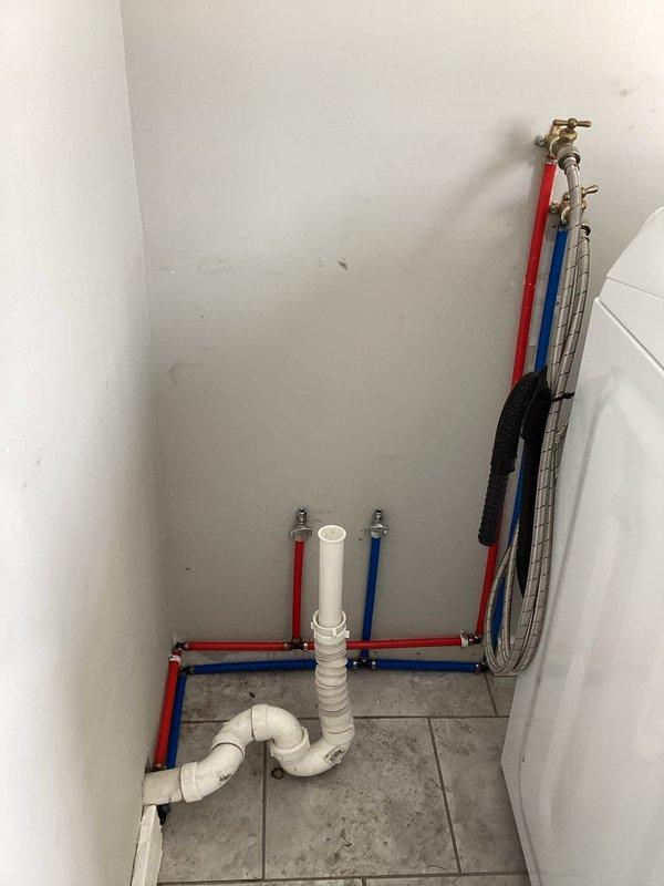 Completed replacement of damaged CPVC piping system with new color-coded PEX water supply lines throughout the basement. Installed proper P-trap drainage assembly with corresponding hot and water supply lines terminating at brass shutoff valves for washing machine hookup. All new PEX lines were securely fastened to ceiling joists with appropriate hangers and tested for leaks.
