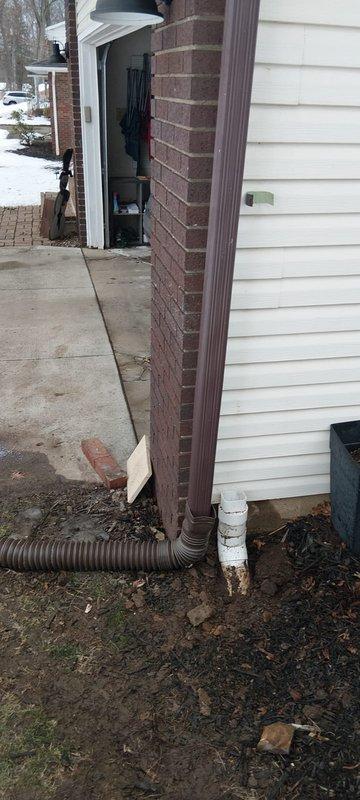 Responded to service call for a clogged and broken downspout line on a 30-year-old home. Upon inspection, found damaged connector at the base of the downspout where it meets the ground drainage system. Installed new PVC downspout drainage components, ensuring proper connection between the rectangular upper section and the round pipe below to restore proper water flow away from the foundation.