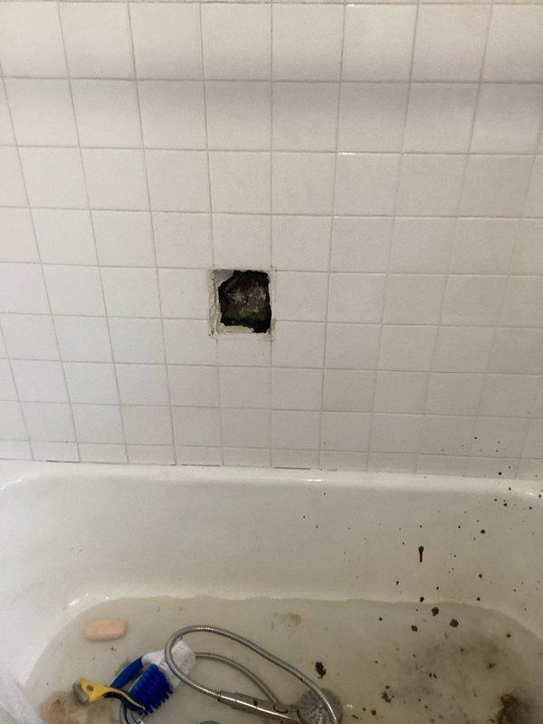 Responded to a water leak call at a 35-year-old residence involving a bathtub drain. Upon inspection, accessed plumbing through a removed wall tile and identified aging P-trap assembly in the utility area showing signs of water damage and deterioration at ceiling connection. Replaced compromised drain components, sealed connections properly, and verified system integrity with leak test before completing the repair.