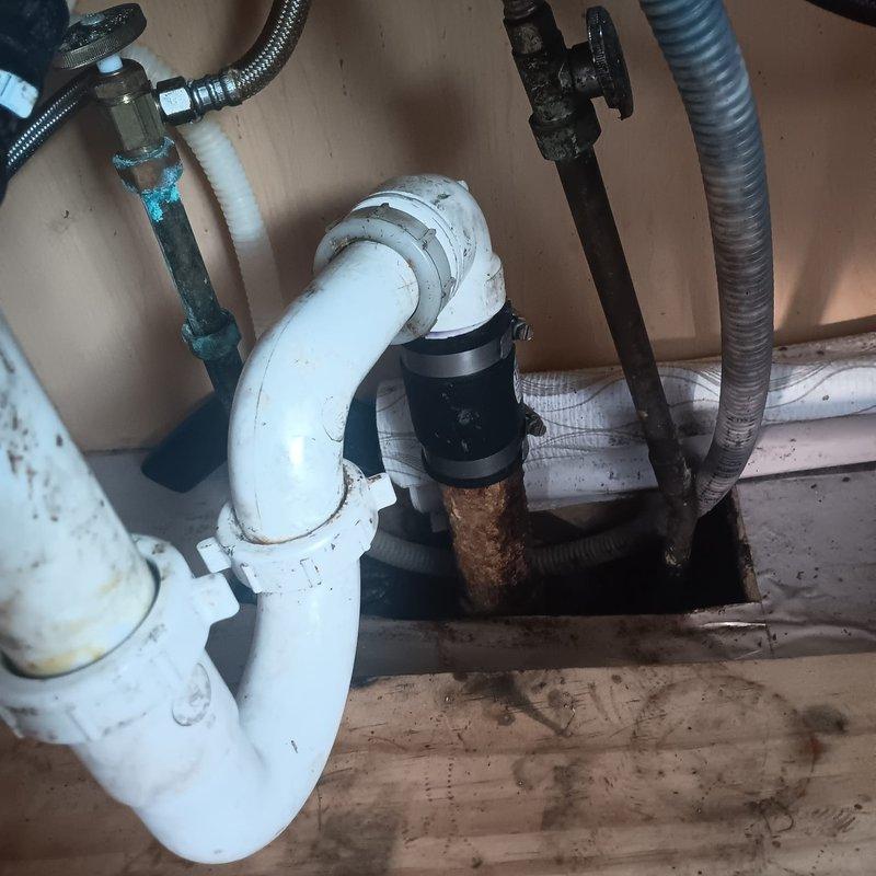 Responded to service call for kitchen drain backup. Inspection revealed significant corrosion on metal fittings connecting to the P-trap assembly, with visible mineral deposits and deterioration of connecting valve. Removed affected components, cleaned accumulated debris from P-trap, and replaced corroded metal fittings with new parts to restore proper drainage function.