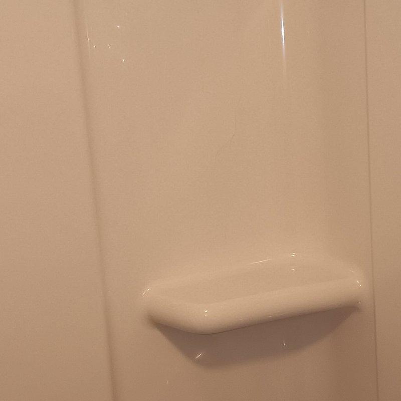 Inspected newly installed tub (installed approximately one week ago) and documented a vertical crack in the lower portion of the tub wall where water contact occurs. Photographed damage for documentation purposes, confirming the presence of a crack in the PCB (Prefabricated Composite Bathing) unit at the point of water impact.