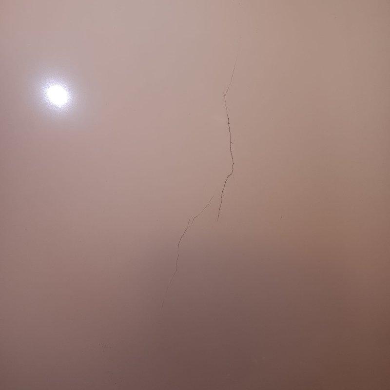 Inspected newly installed tub (installed approximately one week ago) and documented a vertical crack in the lower portion of the tub wall where water contact occurs. Photographed damage for documentation purposes, confirming the presence of a crack in the PCB (Prefabricated Composite Bathing) unit at the point of water impact.