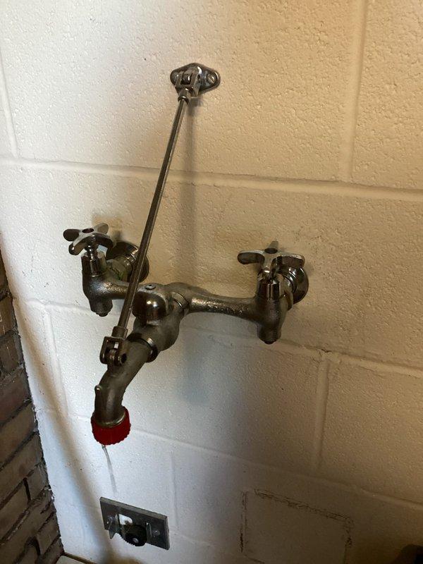 Responded to service call for clogged drain in men's restroom where preliminary work had been started by another technician. Completed drain clearing in the restroom and serviced a utility sink faucet with weathered cross-handle valves and red cap adapter. Additionally, addressed flush meter issues on urinal to restore proper functionality.