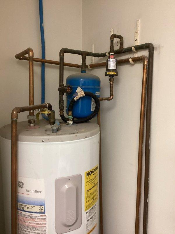 Responded to service call regarding a water leak at the water heater. Upon inspection, identified the source of the leak and documented the existing plumbing configuration, including the P-trap drain system and the GE SmartWater heater installation with expansion tank. Provided customer with quote for necessary repairs, which will require removal of utility sink to complete the project.