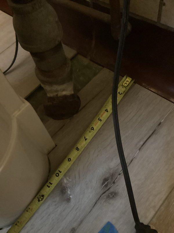 Assessed existing bathroom infrastructure for new shower installation in basement. Evaluated 2" drain in floor and verified presence of hot and cold water supply lines. Documented current plumbing configuration including pipe connections and drainage system to determine feasibility of fixture addition.