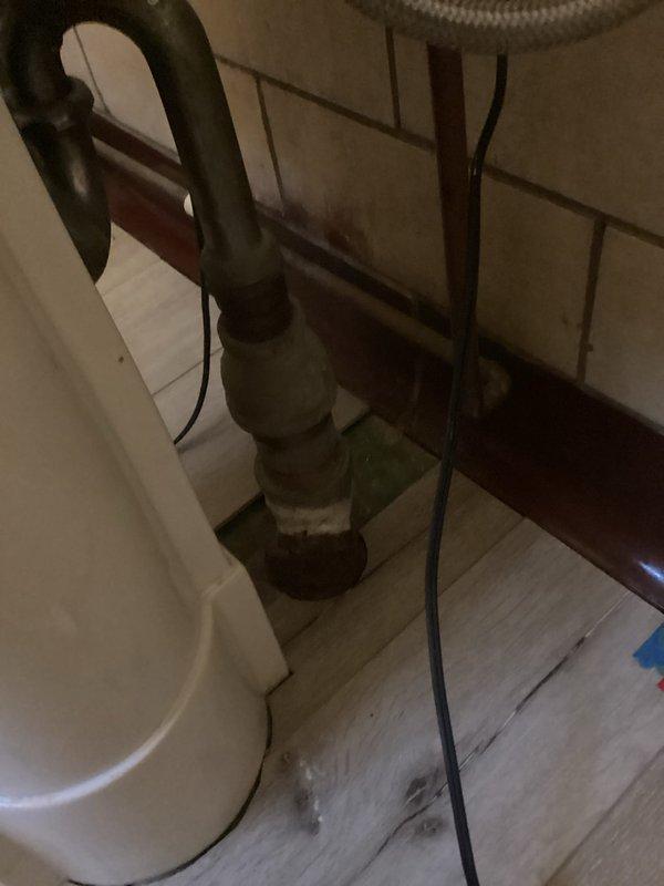 Assessed existing bathroom infrastructure for new shower installation in basement. Evaluated 2" drain in floor and verified presence of hot and cold water supply lines. Documented current plumbing configuration including pipe connections and drainage system to determine feasibility of fixture addition.
