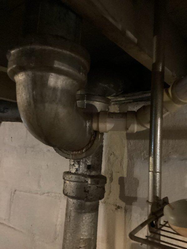 Responded to main drain cleanout service request at a century home. Inspected the aged plumbing system, which featured metal waste pipes with curved P-trap configuration and multiple connection points showing signs of wear. Successfully cleaned the main drain line, restoring proper drainage function to the historical plumbing system.