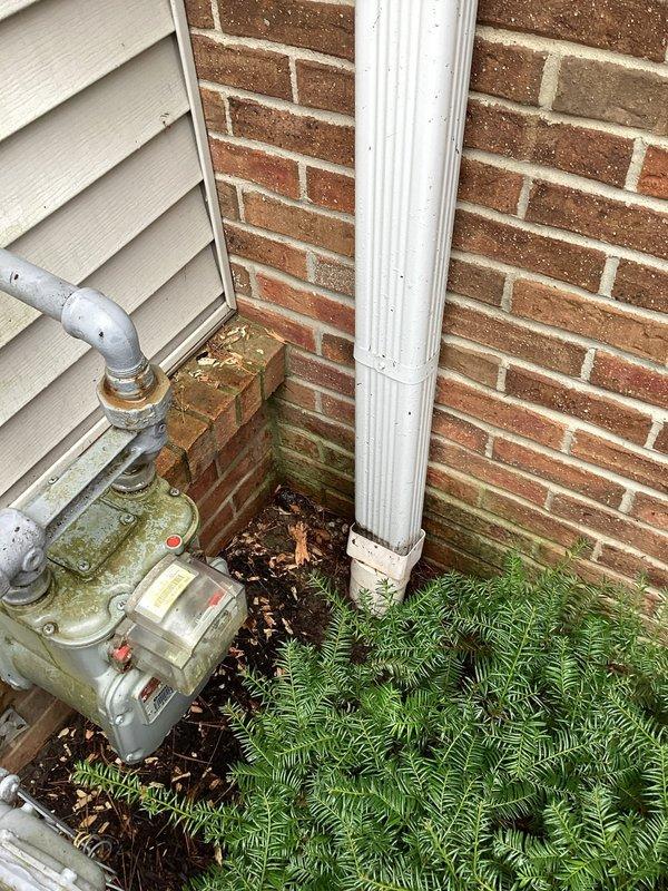 Responded to service call for clogged exterior downspout. Cleared accumulated organic debris (leaves and twigs) from the downspout system and removed blockage causing water backup. Noted oil staining on adjacent concrete surface that appears unrelated to the downspout issue.