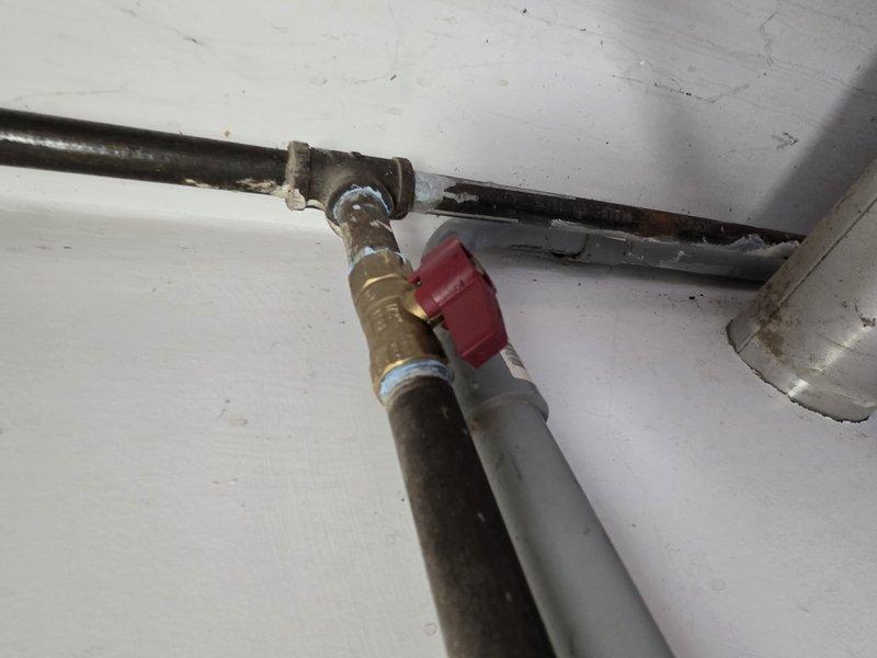 Completed installation of approximately 90 feet of 1-1/2" gas piping inside the structure. Installed a red-handled shutoff valve at the T-junction where the new gas line connects to the existing metal supply pipe. Documented installation with photos showing proper connection points and valve placement under winter conditions.