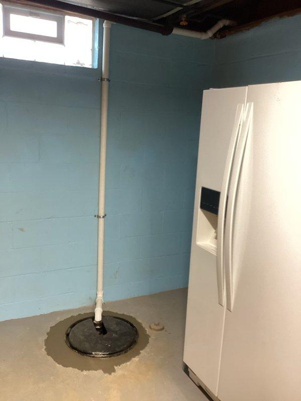 Installed new sump crock in basement utility room, connecting it to existing PVC drainage system. Proper installation included cutting appropriate opening in floor and ensuring secure fit of black plastic crock with ridged interior walls. Verified drainage functionality after installation complete.