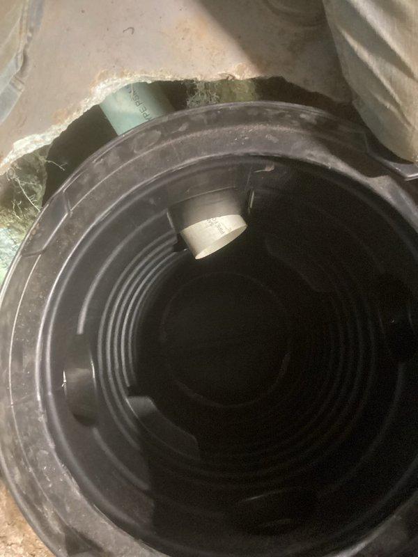 Installed new sump crock in basement utility room, connecting it to existing PVC drainage system. Proper installation included cutting appropriate opening in floor and ensuring secure fit of black plastic crock with ridged interior walls. Verified drainage functionality after installation complete.