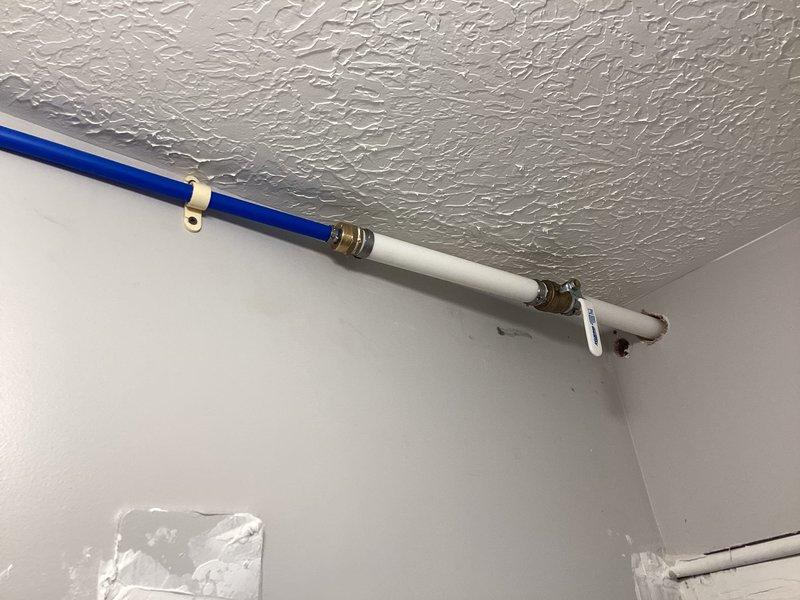 # Plumbing Service Report

Installed new floor drain with drainage piping routed under walls to connect with main stack located in closet behind furnace. Upgraded water supply line from 1/2-inch to 1-inch, running from adjacent commercial space across ceiling and into bathroom area. Installation included PEX piping with secure mounting brackets and inline filtration components with brass fittings for proper water flow and quality control.