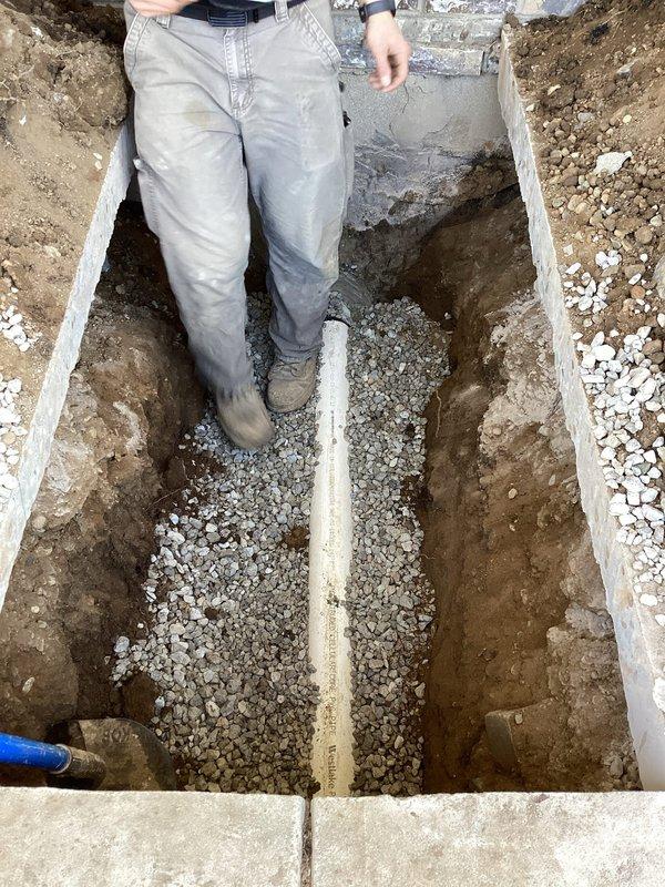 Excavated and exposed existing sewer line to locate and repair damaged section. Installed new white PVC piping with proper fittings and elbow joints, bedded in crushed stone aggregate within properly dimensioned trench. Verified integrity of remaining pipe system and backfilled excavation upon completion of repairs.