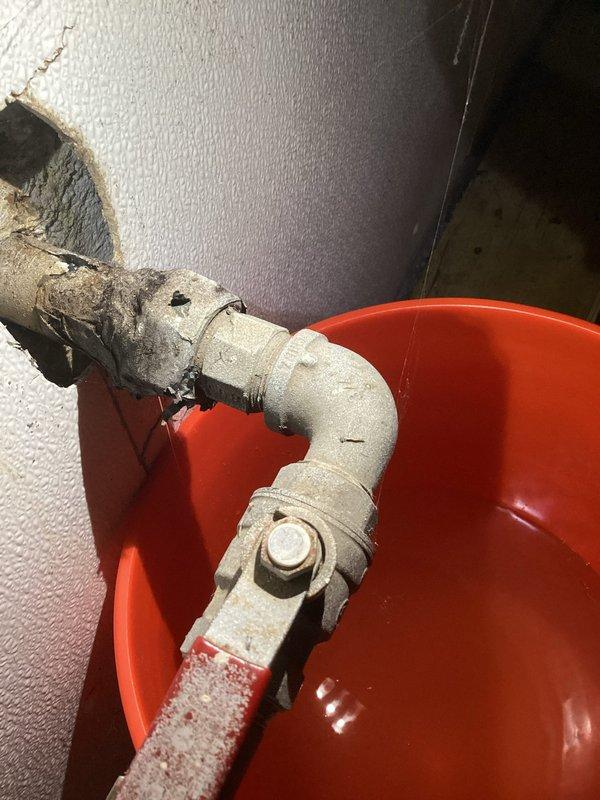 Responded to water leak located before the water meter inside the property. Upon arrival, found active leak at pipe connection with deteriorated insulation material exposing the underlying pipe. Placed collection bucket to contain water flow and prevent further property damage. Inspected plumbing assembly including pump unit, piping connections, and shutoff valve to assess leak source and extent of repairs needed.