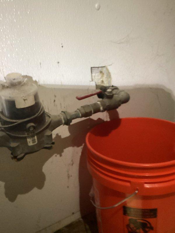 Responded to water leak located before the water meter inside the property. Upon arrival, found active leak at pipe connection with deteriorated insulation material exposing the underlying pipe. Placed collection bucket to contain water flow and prevent further property damage. Inspected plumbing assembly including pump unit, piping connections, and shutoff valve to assess leak source and extent of repairs needed.