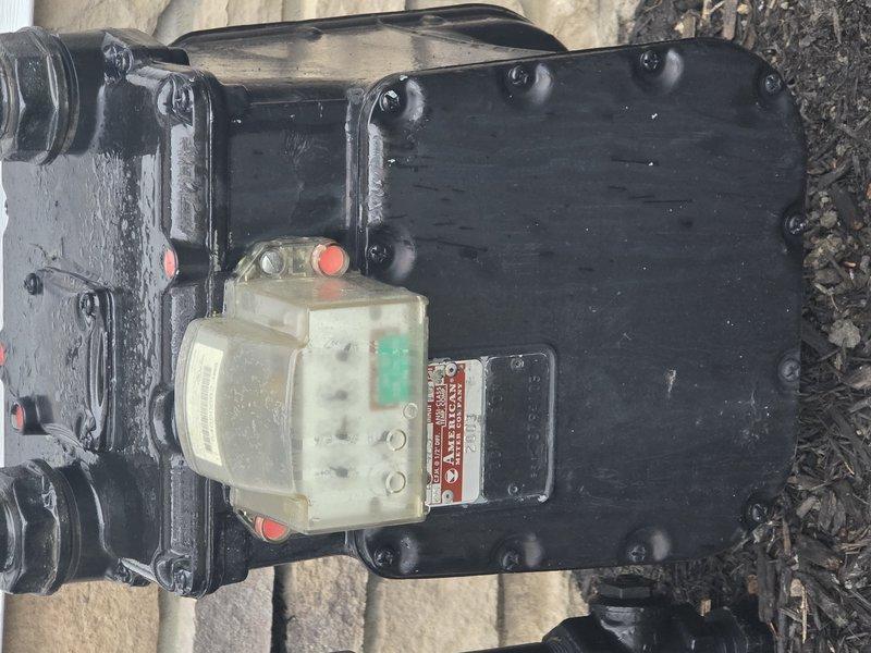 Completed installation of approximately 20 feet of underground gas piping with 1-inch risers to exterior building wall. Installed black iron pipe assembly with multiple fittings, pressure regulator, and meter connection point, mounting entire configuration at the junction between white siding and stone veneer exterior. All connections were properly fitted, tested, and secured according to code requirements for residential gas service.