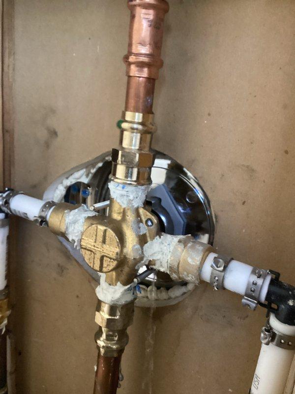 Responded to water leak emergency affecting bathroom ceiling. Upon inspection, identified active leak originating from bathtub plumbing causing significant water damage to ceiling below, evidenced by yellowish-brown staining and compromised drywall integrity. Accessed plumbing assembly and discovered leak at shower valve manifold connection points. Applied temporary sealing compound to brass fittings and PEX connections to stop active water intrusion. Documented existing ceiling damage and plumbing configuration for follow-up repair work. Secured property upon completion as requested.