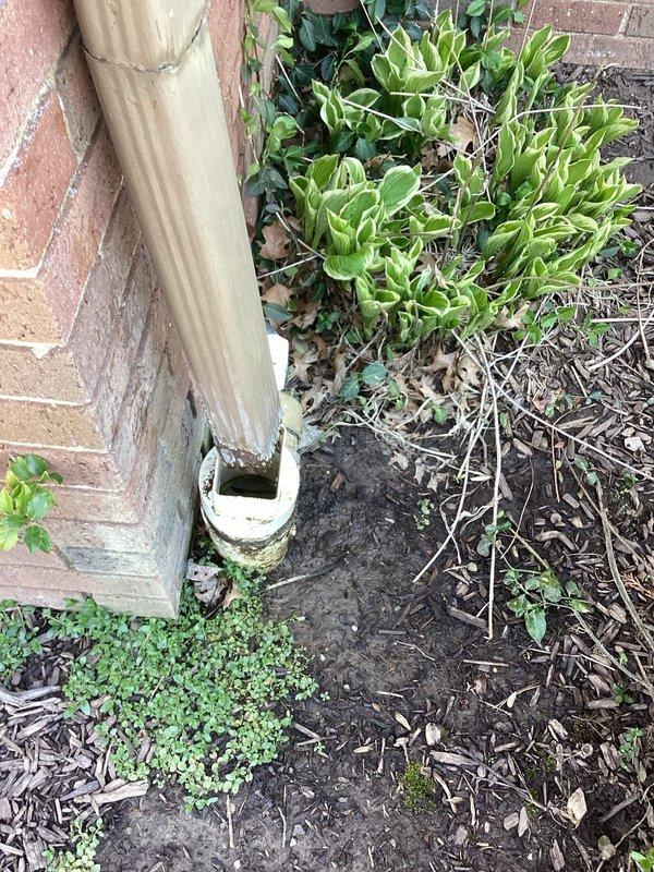 Performed camera inspection of exterior ABS drainage line at foundation level. Documented downspout connection point and horizontal drain pipe assembly where weathered PVC coupling joins corrugated metal downspout to underground drainage system. Identified repair location at base of building where foundation drainage requires attention due to compromised pipe connections in landscaped area.