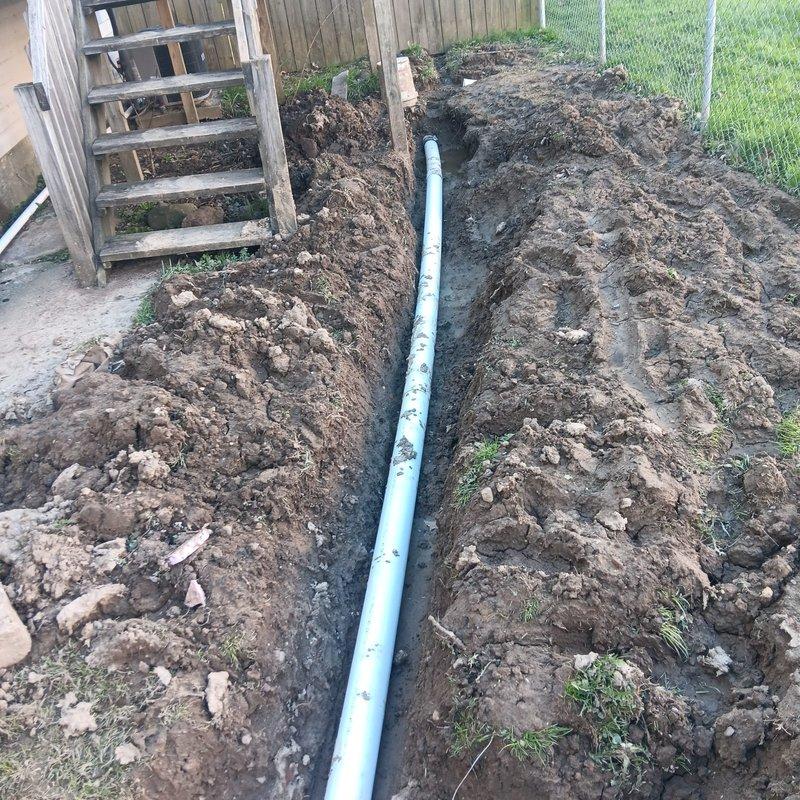 Conducted site assessment and prepared revised estimate for sump pump drainage system that required correction due to improper temporary repairs. Evaluated existing excavation work including blue PVC drainage pipe installation running through backyard trench, assessed condition of disturbed soil and incomplete backfilling, and inspected white PVC piping configuration in secondary excavated area near property perimeter. Documented current system conditions with photographs to develop accurate scope of work for proper remediation and completion of drainage installation.