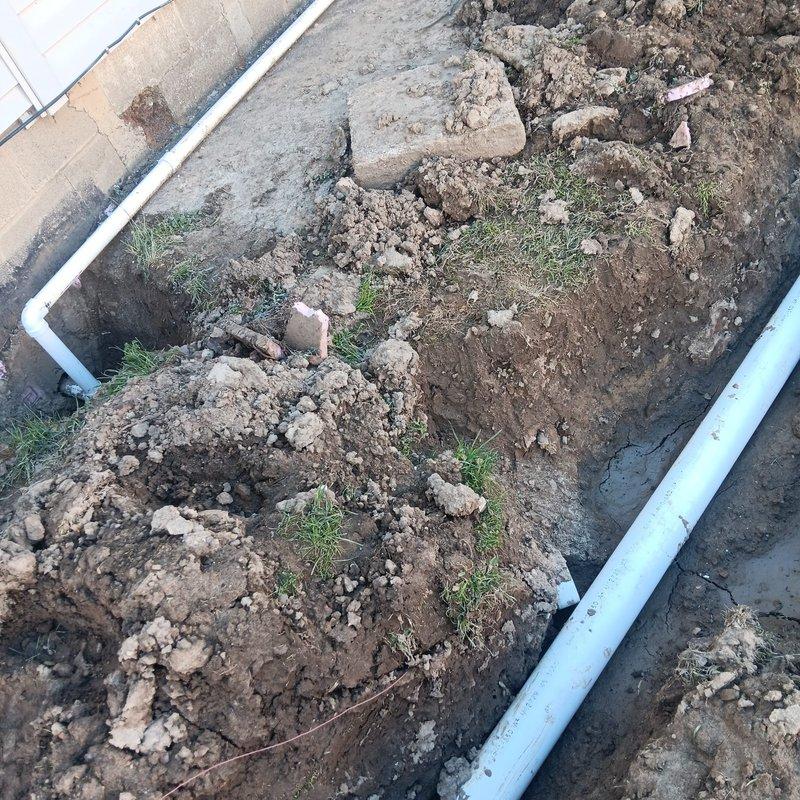 Conducted site assessment and prepared revised estimate for sump pump drainage system that required correction due to improper temporary repairs. Evaluated existing excavation work including blue PVC drainage pipe installation running through backyard trench, assessed condition of disturbed soil and incomplete backfilling, and inspected white PVC piping configuration in secondary excavated area near property perimeter. Documented current system conditions with photographs to develop accurate scope of work for proper remediation and completion of drainage installation.