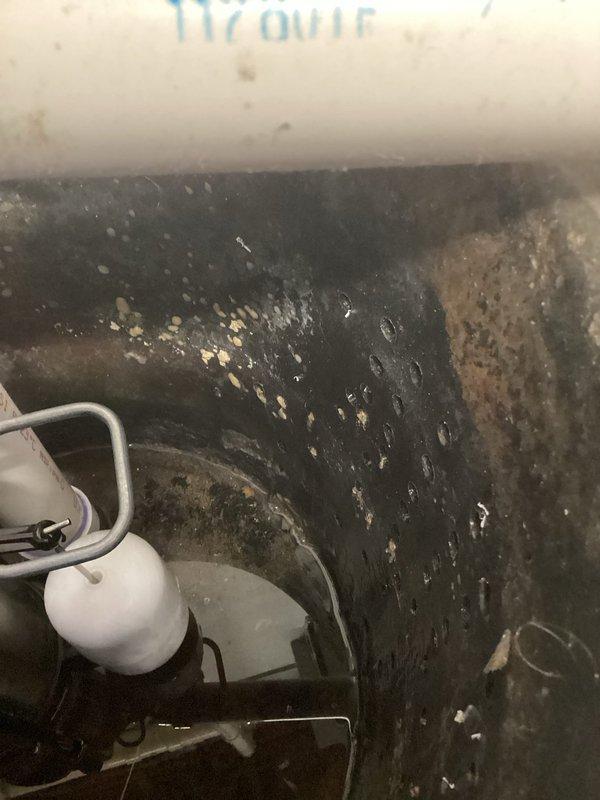 Responded to service call for sump pump evaluation. Upon inspection, found existing sump pump showing signs of burnout with significant deterioration of the basin crock. The sump basin exhibited extensive corrosion on the metal base plate, heavy biological growth including mold and algae buildup throughout the interior surfaces, and substantial rust staining. The float mechanism and discharge piping were assessed for functionality. Documented existing conditions with photographs showing the corroded metal components, contaminated basin surfaces with dark slimy deposits, and mineral accumulation on surrounding surfaces. Provided free estimate for replacement of both the sump pump unit and deteriorated crock basin due to advanced wear and unsanitary conditions that could compromise system performance and reliability.