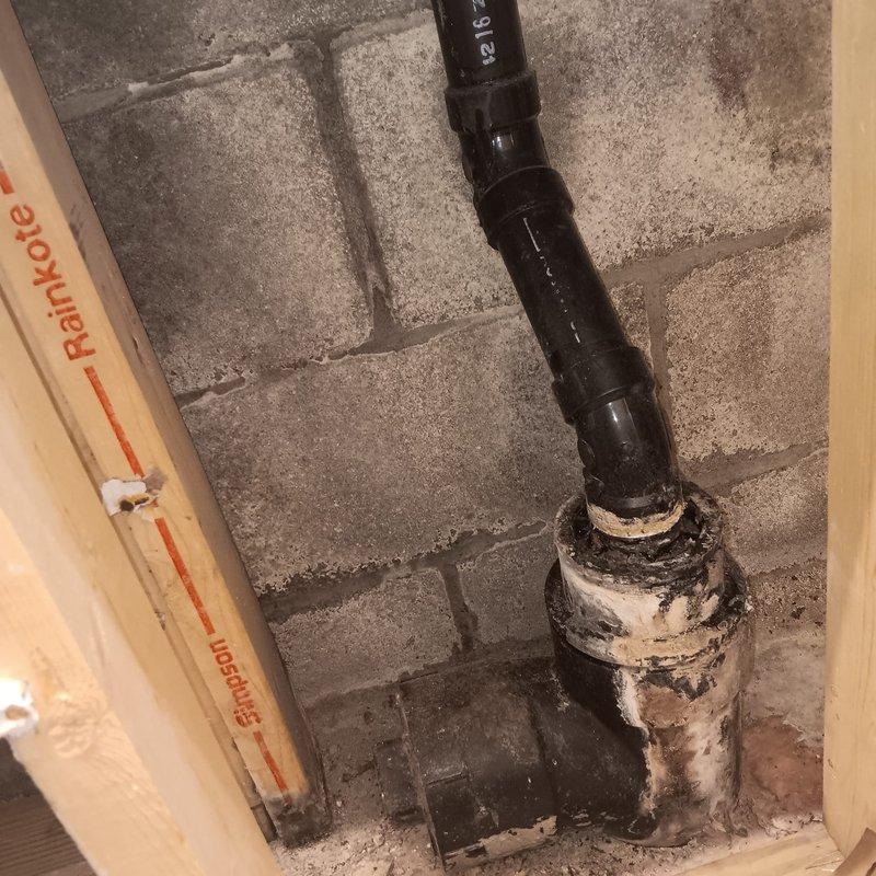 Conducted diagnostic evaluation of residential sewer line experiencing recurring backup issues. Assessed existing plumbing infrastructure in basement utility area, including vertical drain stack and floor-level sewer connections. Documented deteriorated condition of existing piping system, noting severely degraded paint, corrosion, and wear on junction components where vertical stack meets floor penetration. Identified aging cast iron or clay piping system requiring backwater valve installation to prevent sewage backflow into property. Photographed current plumbing configuration and condition of concrete floor penetrations and wall-mounted drainage components to develop installation plan for backwater valve assembly.