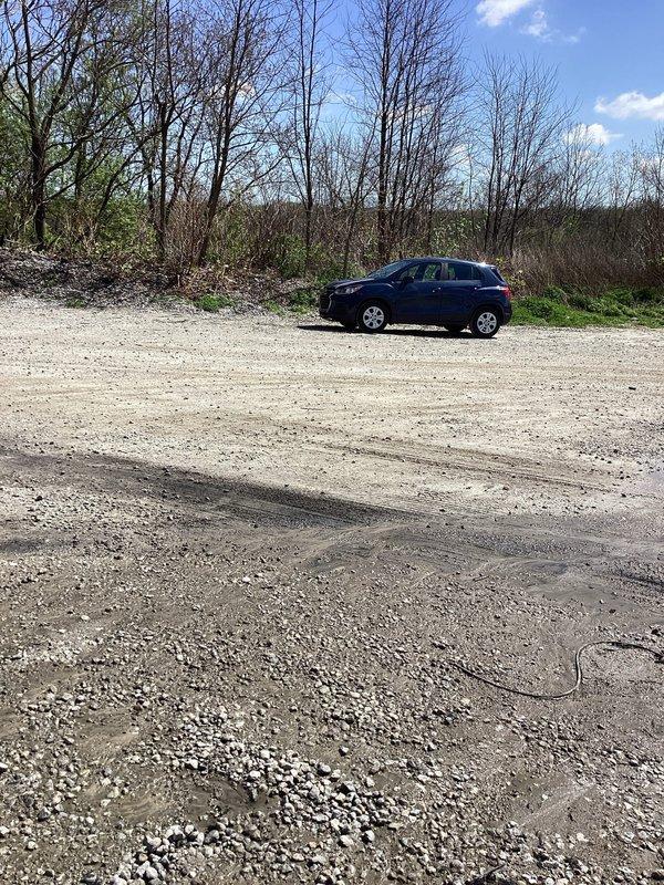 Responded to service call for ground water drainage assessment at commercial property. Upon arrival, checked in at office as requested and proceeded to inspect the exterior drainage system located on the side of the building. 

Performed diagnostic evaluation of existing floor drain installed in concrete pavement. Found drain cavity containing significant standing water with murky appearance, indicating inadequate drainage capacity or potential blockage in downstream piping. Observed weathered concrete frame surrounding drain opening with visible structural deterioration including multiple cracks, chips, and surface degradation. Noted accumulation of debris and sediment within drain opening and around perimeter, partially obstructing flow. Dark drainage component visible within cavity but submerged conditions prevented full assessment of internal mechanism functionality.

Documented extensive cracking in surrounding pavement radiating outward from drain location, suggesting possible se