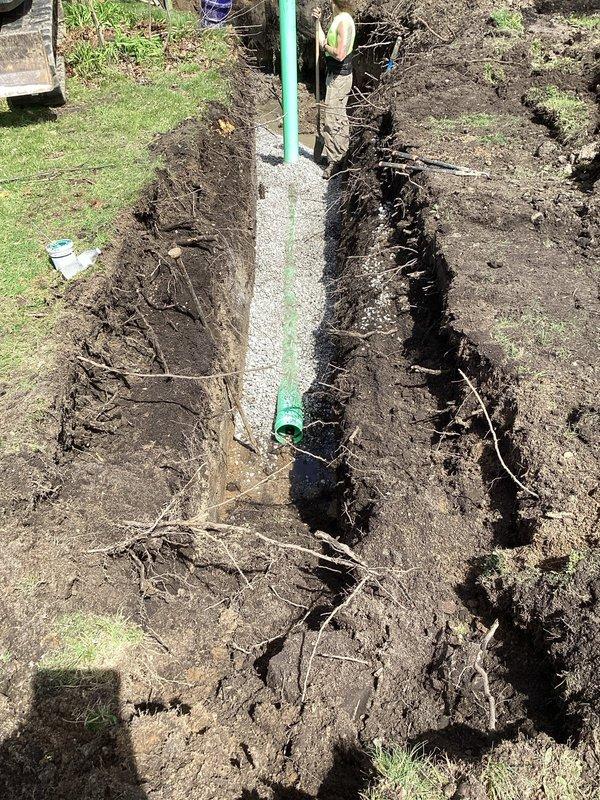 Completed sewer conversion by installing sanitary sewer lateral from existing tap to main drain, replacing the property's septic system. Excavated trench to proper depth and specifications, installed green PVC piping with appropriate bedding material consisting of gravel base for proper drainage and pipe support. Pumped and crushed two existing septic tanks per project requirements. Obtained sanitary sewer lateral permit from City of Akron prior to commencement of work. Ensured all installations met municipal code requirements and prepared site for inspection. Trench excavation revealed clean soil cuts through multiple layers, with piping installed vertically and horizontally as needed for proper connection to municipal sewer main. Gravel bedding properly placed at trench bottom to provide stable foundation for lateral line. All work performed in accordance with local plumbing codes and ready for final municipal inspection.