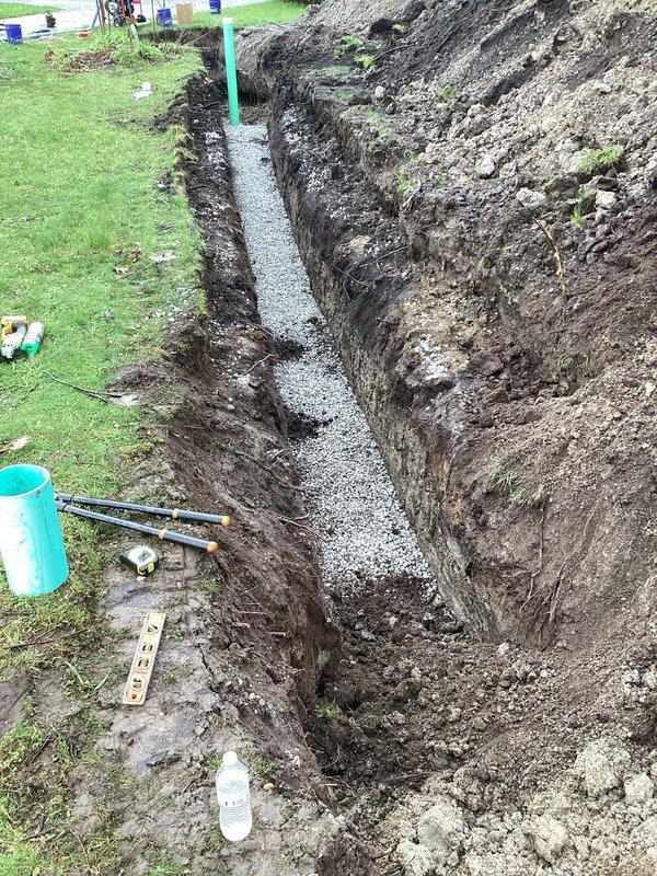 Completed sewer conversion by installing sanitary sewer lateral from existing tap to main drain, replacing the property's septic system. Excavated trench to proper depth and specifications, installed green PVC piping with appropriate bedding material consisting of gravel base for proper drainage and pipe support. Pumped and crushed two existing septic tanks per project requirements. Obtained sanitary sewer lateral permit from City of Akron prior to commencement of work. Ensured all installations met municipal code requirements and prepared site for inspection. Trench excavation revealed clean soil cuts through multiple layers, with piping installed vertically and horizontally as needed for proper connection to municipal sewer main. Gravel bedding properly placed at trench bottom to provide stable foundation for lateral line. All work performed in accordance with local plumbing codes and ready for final municipal inspection.