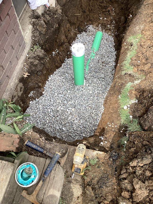 Completed exterior sanitary sewer lateral replacement from house foundation to right of way. Performed camera inspection and locating services to identify existing sewer line running between houses toward front of property. Excavated trench along left side of house, removing section of sidewalk as necessary for access. Installed new SDR 35 solid PVC pipe with appropriate fittings, backfilled with #57 limestone for proper drainage and support. Reconnected new lateral to existing exterior floor drain connection at foundation. Obtained exterior sewer lateral permit and coordinated inspection. All work completed to code specifications with proper bedding and backfill materials.